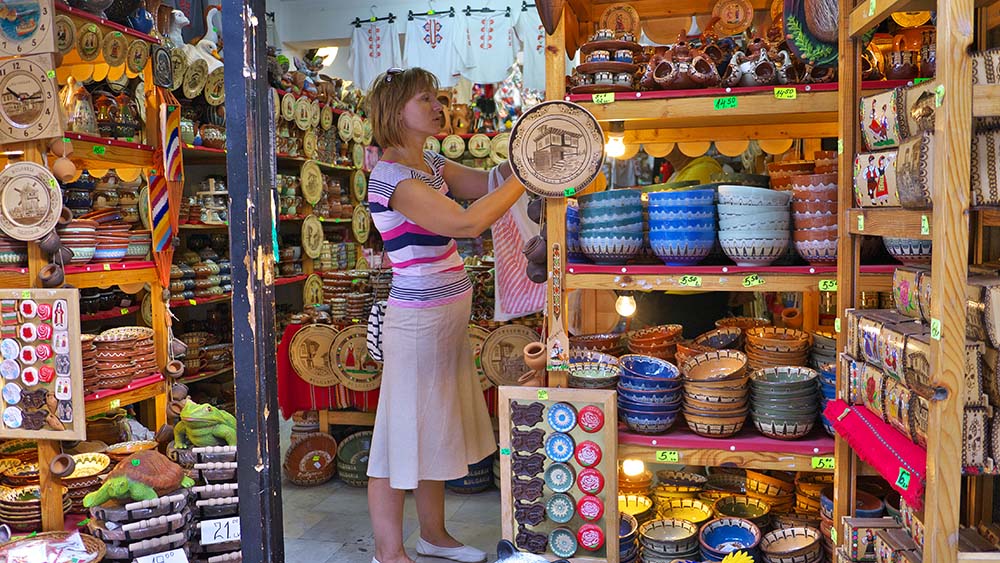 Молодая женщина выбирает сувениры в Несебре.
