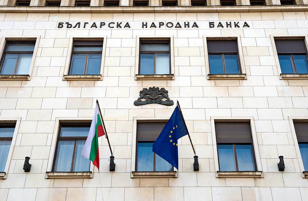 Здание болгарского банка для ипотечных услуг Современное здание болгарского банка с классическим фасадом, колоннами и симметричной архитектурой под ясным голубым небом