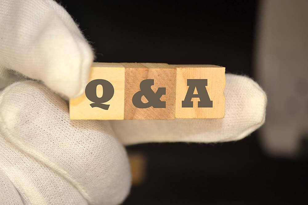 Руководство вопросов и ответов покупателя Рука держит деревянные блоки Q&A представляя исчерпывающие вопросы покупателей недвижимости и экспертные