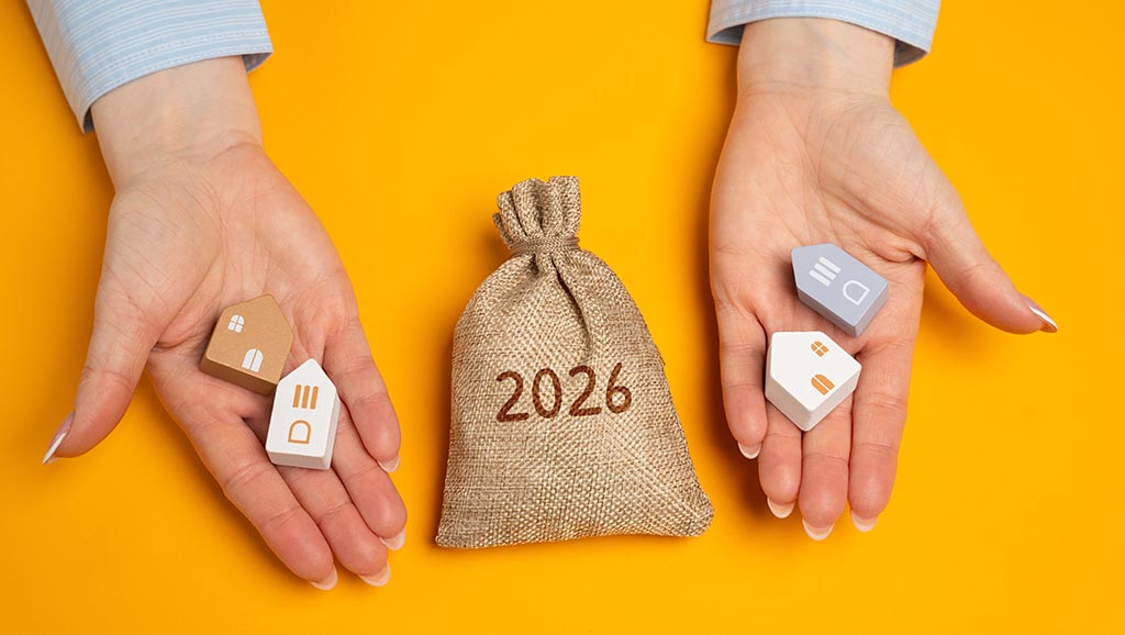 Руки держат макеты домов и мешок с деньгами, отражая финансовые аспекты покупки недвижимости в Болгарии