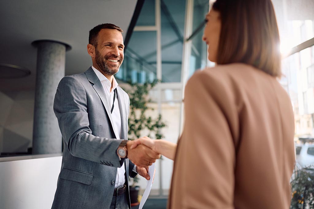 Мужчина и женщина пожимают руки, фиксируя официальное соглашение о покупке недвижимости в Болгарии